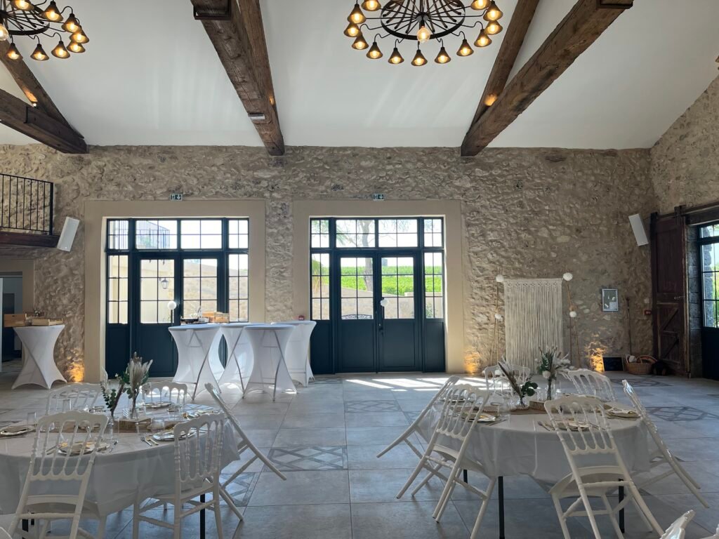 Salle réception pierres apparentes poutres bois tables rondes décorées Domaine de Lastours Béziers mariage Hérault Occitanie