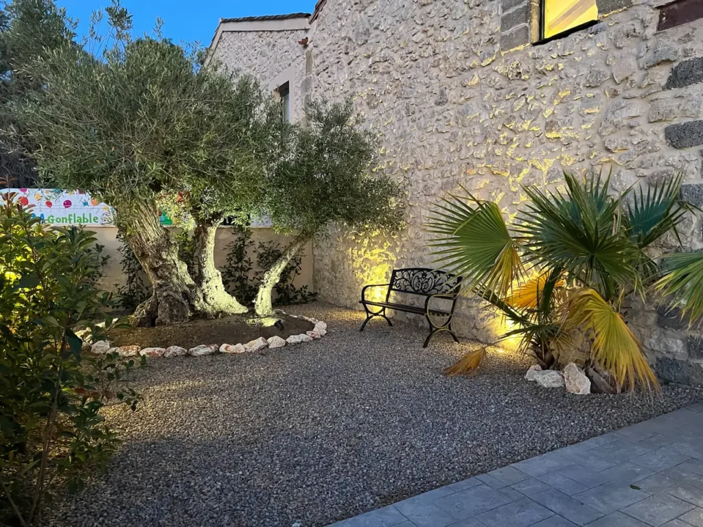 Jardin méditerranéen mur pierre olivier palmier banc fer forgé éclairage ambiance Domaine de Lastours Béziers mariage Hérault Occitanie