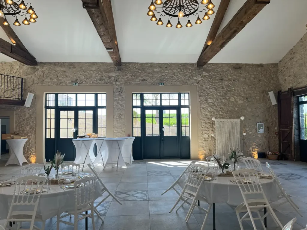 Salle réception pierres apparentes poutres bois tables rondes buffet Domaine de Lastours Béziers mariage Hérault Occitanie