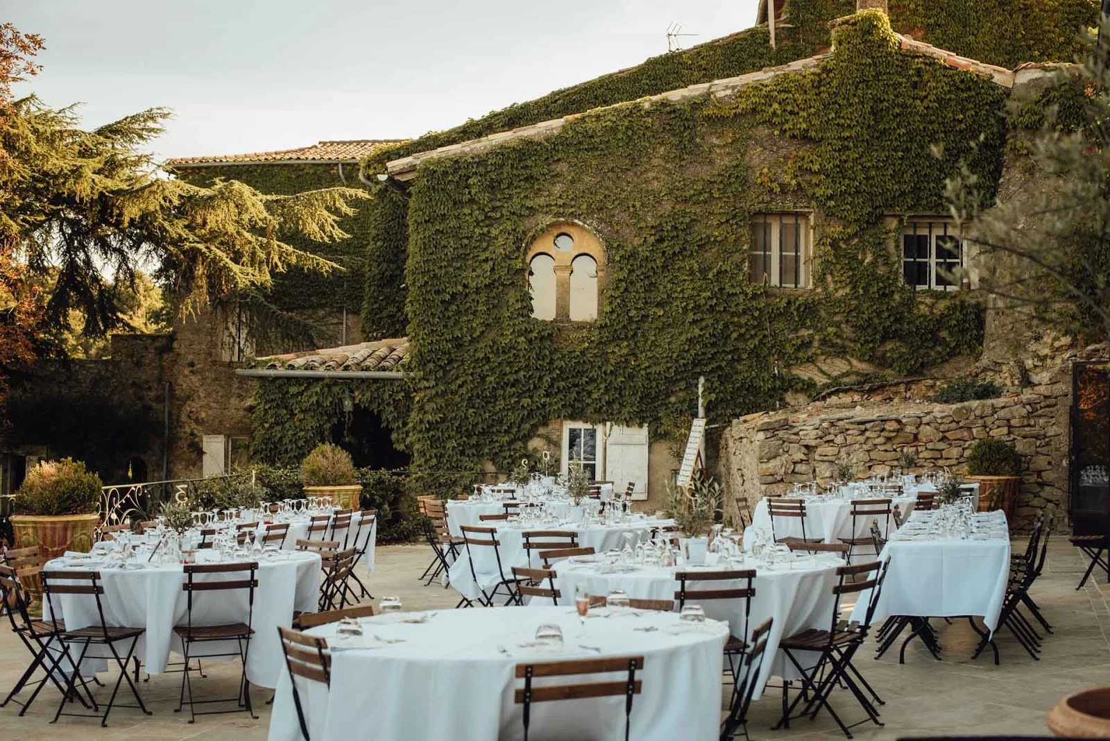 Repas de mariage en terrasse extérieure du Château Bas d'Aumelas avec façade en lierre et fenêtre romane en Hérault