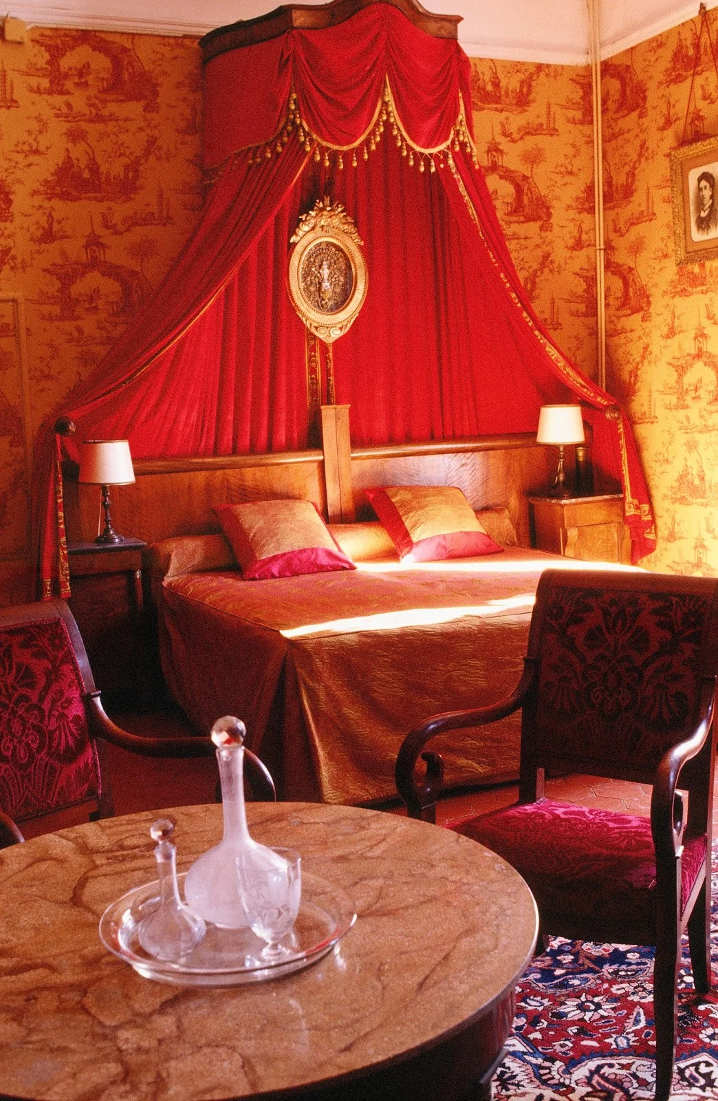 Chambre avec lit baldaquin rouge et or du Château d'Agel, hébergement de luxe pour mariage en Hérault