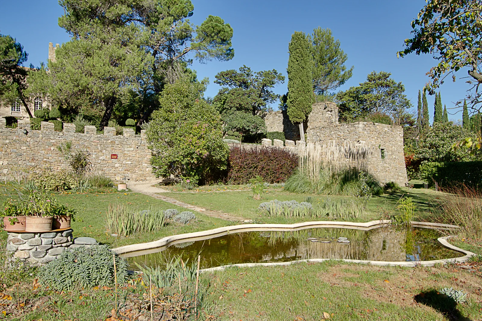 Jardin du Château d'Agel avec pièce d'eau, pelouse et remparts médiévaux, cadre naturel pour mariage en Hérault