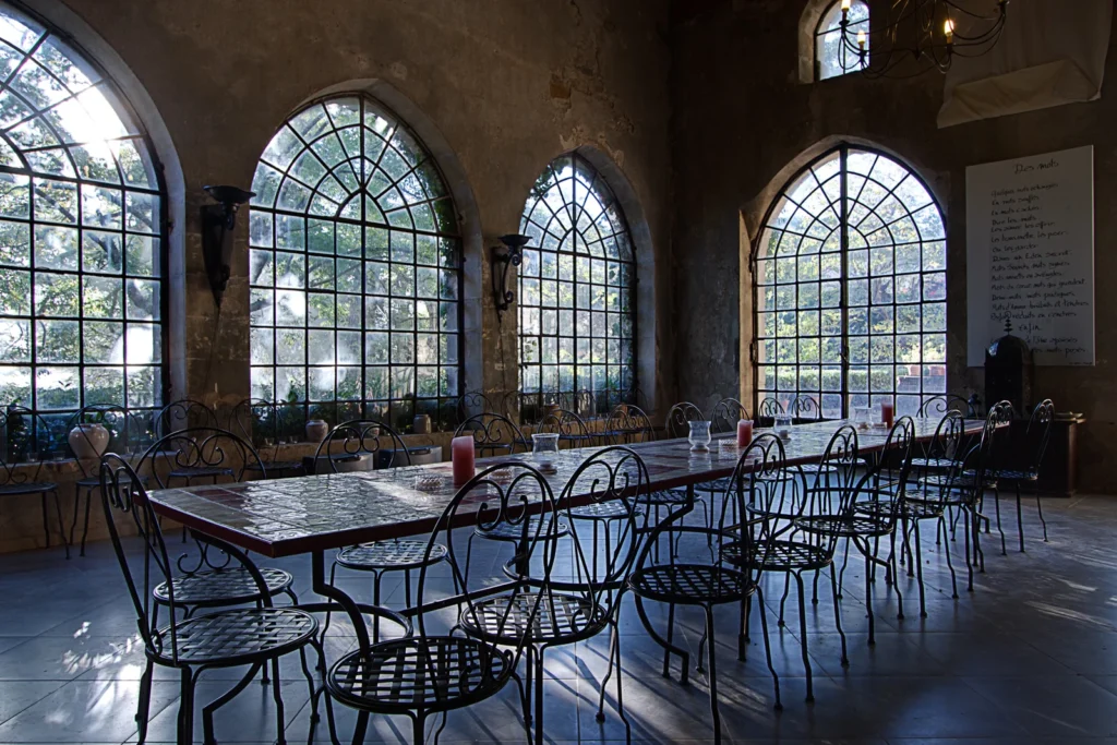 Orangerie du Château d'Agel avec grandes fenêtres en arc et tables dressées, salle de réception pour mariage en Hérault