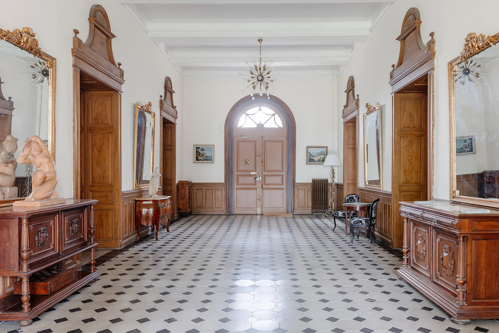 Hall d'entrée monumental du Château de Bayssan avec boiseries et miroirs dorés pour réception de mariage en Hérault