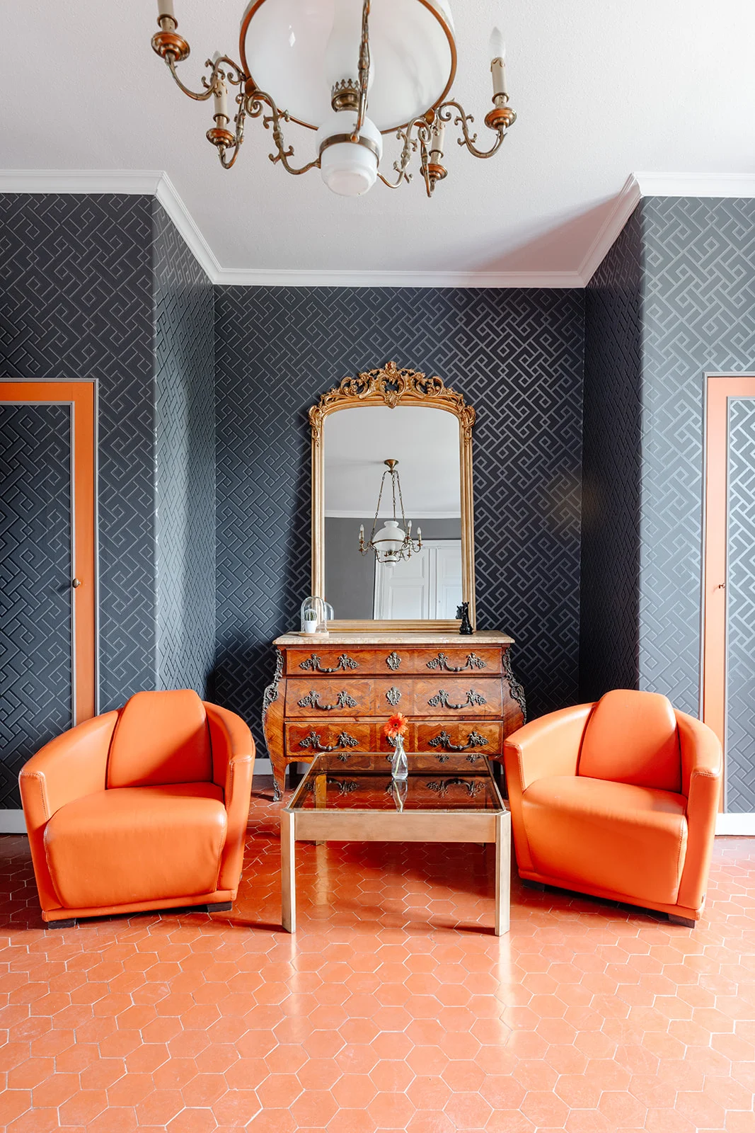 Salon du Château de Bayssan avec fauteuils orange, miroir doré baroque et tomettes, décoration mariage Hérault