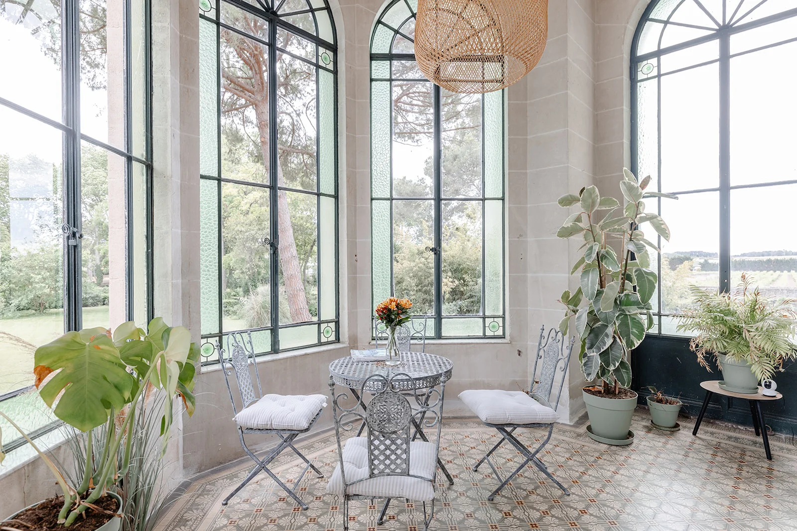 Véranda lumineuse du Château de Bayssan avec verrières cintrées et plantes, espace cocktail mariage Hérault