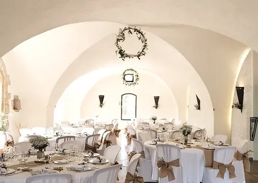 Salle de réception voûtée du Château de Coussergues décorée pour un mariage, tables rondes et chaises blanches, Hérault