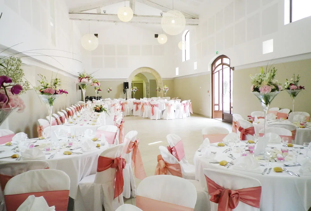 Grande salle de réception décorée, tables rondes, chaises roses, fleurs, Château de la Mogère Montpellier mariage Hérault Occitanie