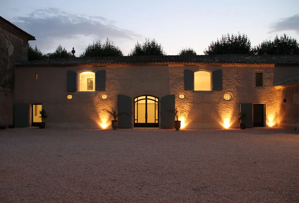Façade pierre, fenêtres volets bleus, cour graviers, éclairage chaud, ambiance romantique Château de la Mogère Montpellier mariage Hérault Occitanie