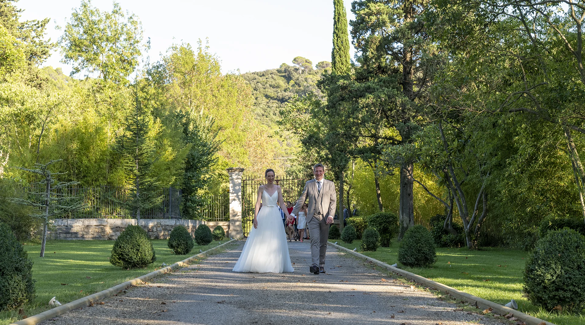 Couple de mariés marchant sur l'allée du parc du Château de Malmont dans l'Hérault lumière dorée
