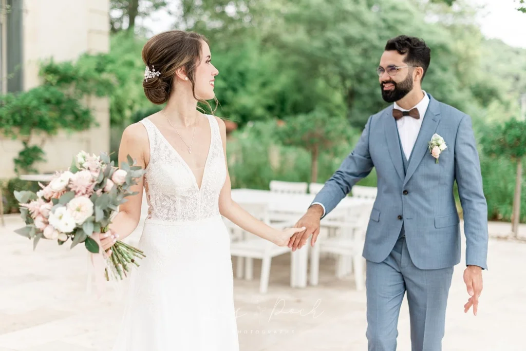 Couple de mariés se tenant la main dans la cour du Château de Malmont Hérault - mariage élégant