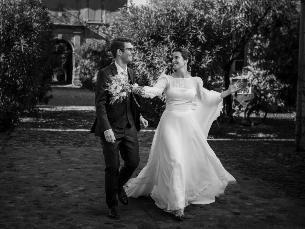 Couple de mariés marchant dans la cour pavée du Château de Malmont Hérault - photo noir et blanc