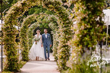 Couple de mariés sous la pergola fleurie de jasmin au Château de Malmont - jardin mariage Hérault