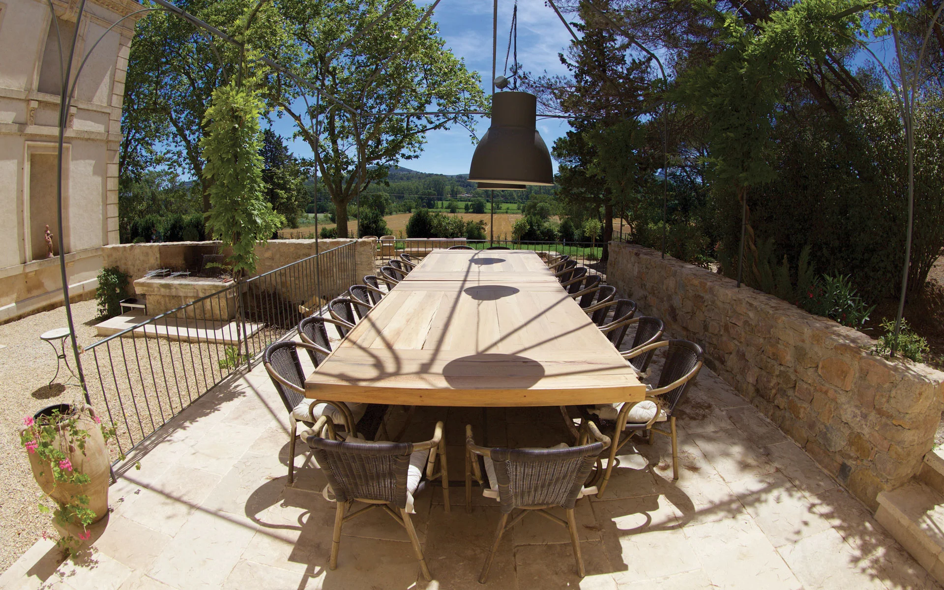 Terrasse extérieure avec grande table en bois et vue panoramique sur les champs au Château de Malmont Hérault