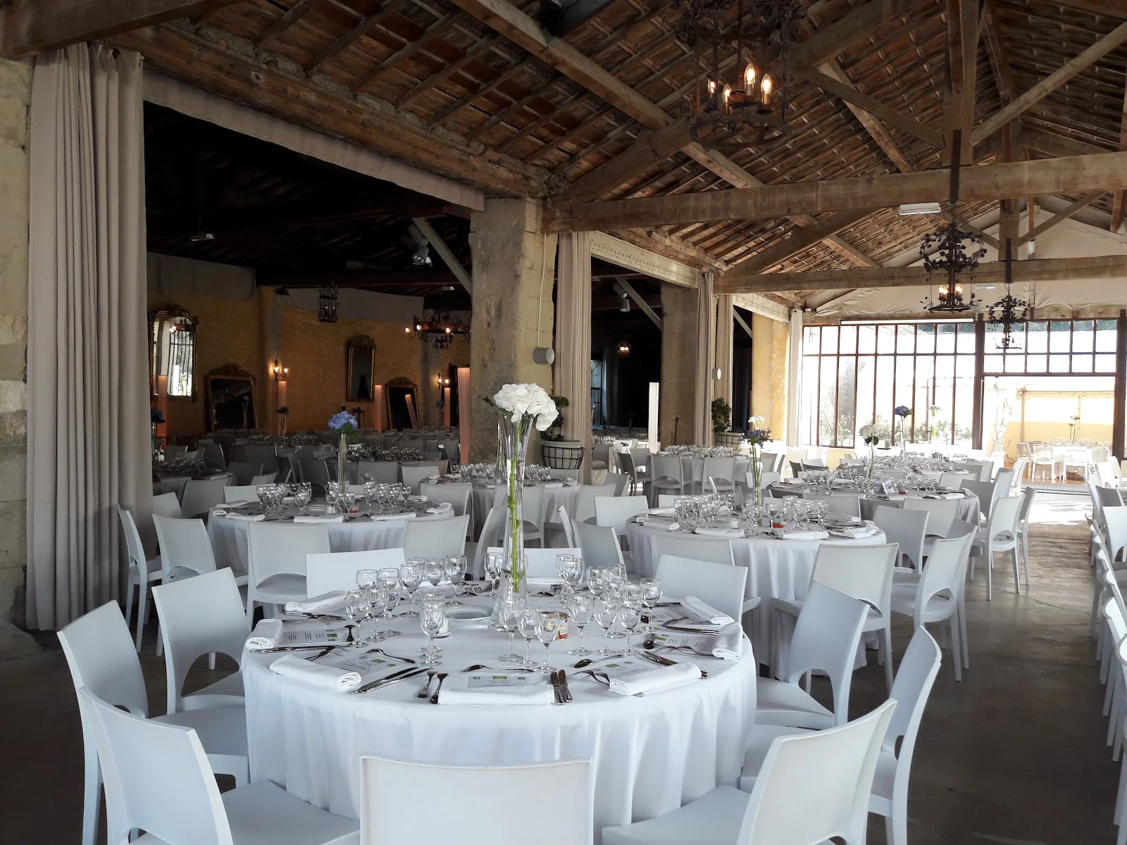 Salle de réception mariage Château de Pouget - tables rondes blanches et charpente bois Hérault
