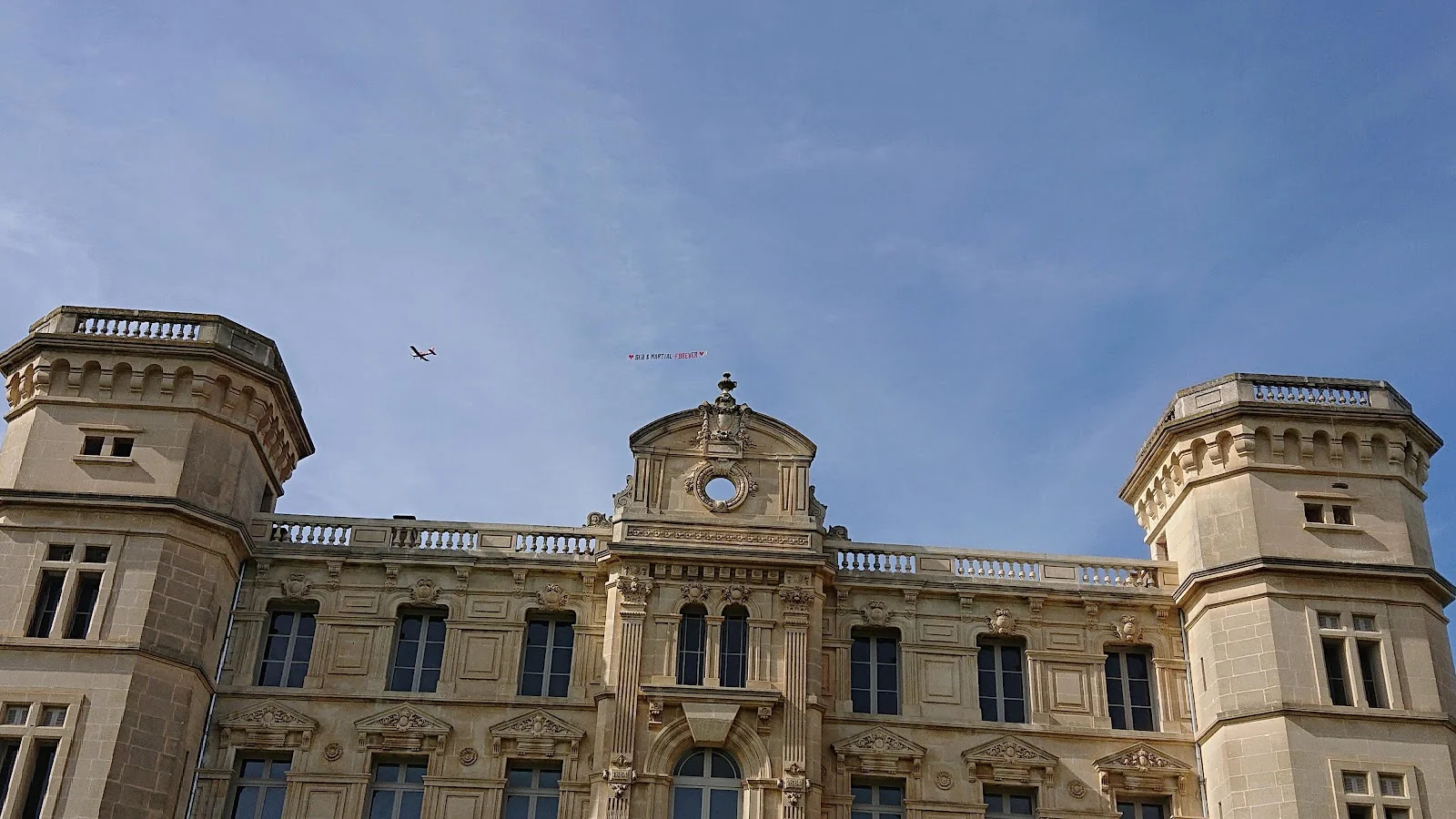 Façade néoclassique du Château de Sériège Hérault avec fronton orné et deux tours sous ciel bleu