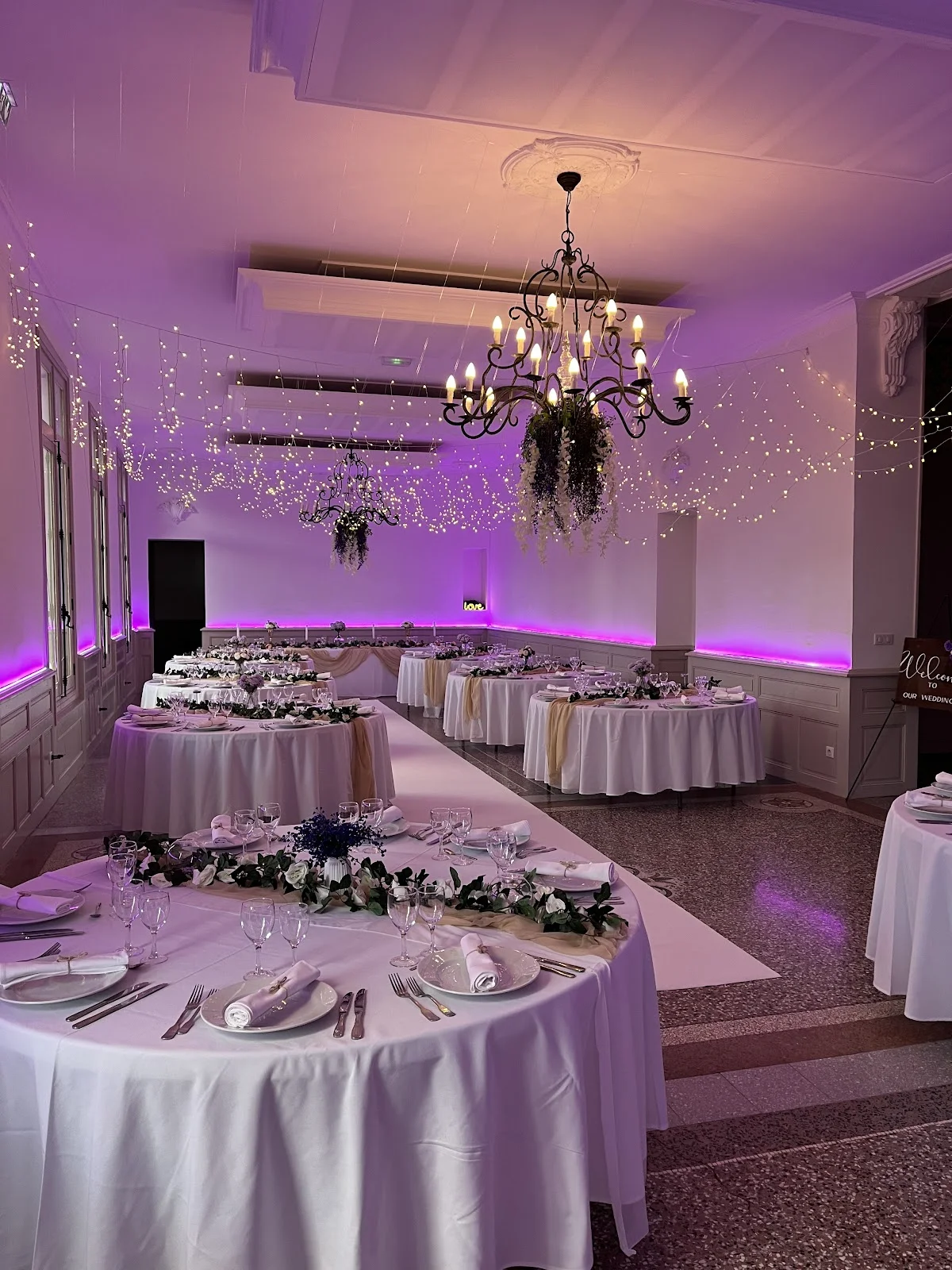 Salle de réception mariage Château de Sériège Hérault décorée en violet avec lustres fer forgé et guirlandes lumineuses