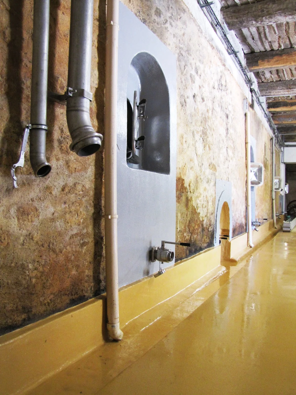 Cave de vinification du Château Domaine du Bosc avec cuves en béton et murs en pierre ancienne en Hérault