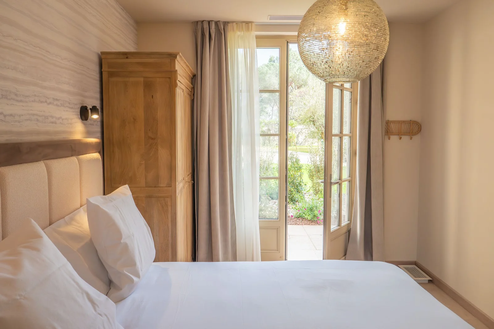 Chambre cosy avec porte-fenêtre ouverte sur le jardin au Château du Parc pour mariage dans l'Hérault