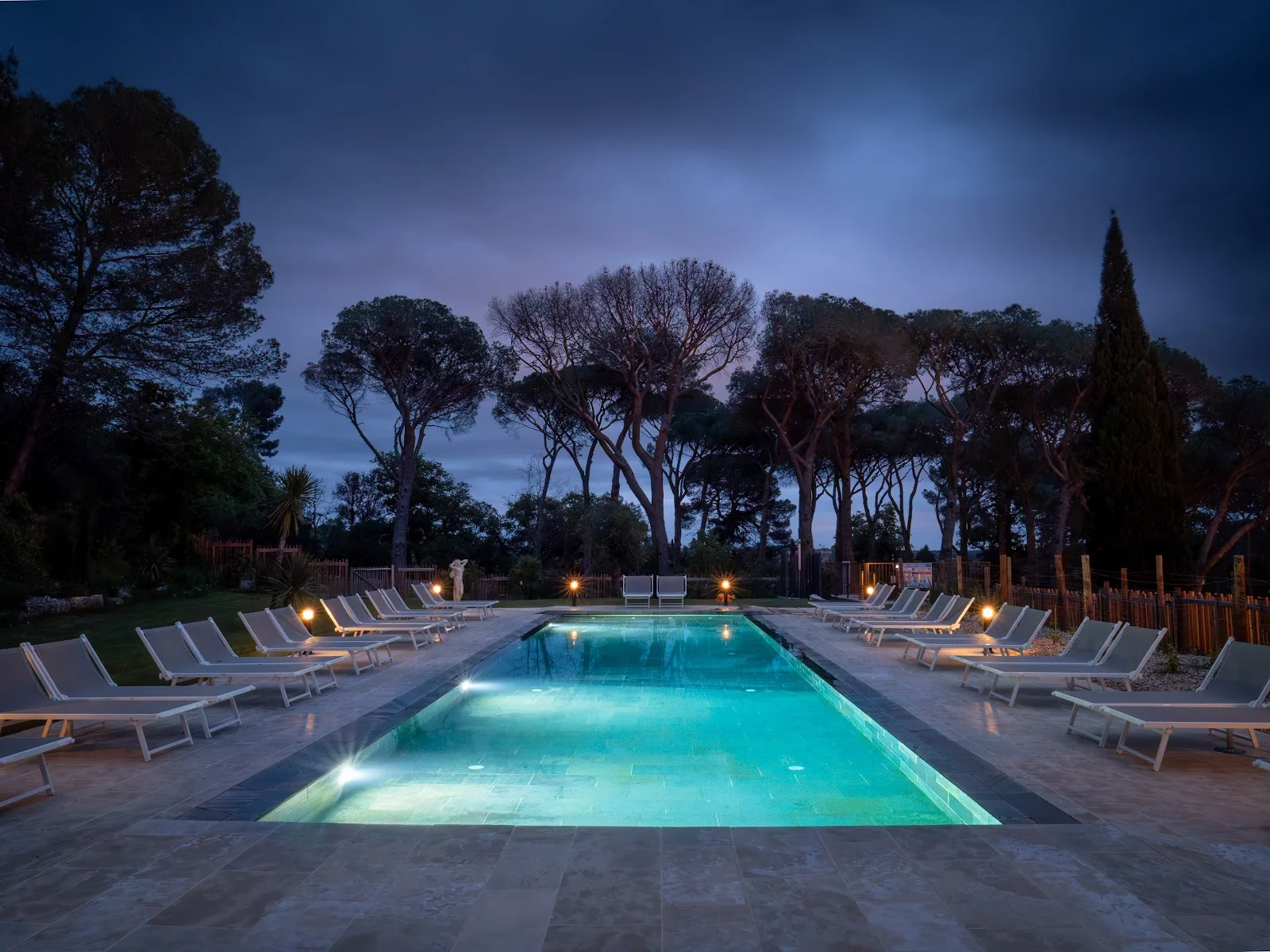 Piscine illuminée la nuit au Château du Parc avec reflets turquoise pour soirée de mariage dans l'Hérault