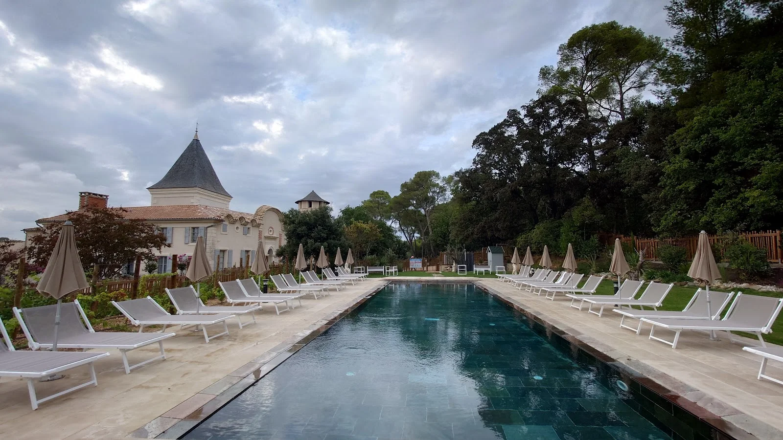 Vue panoramique de la piscine du Château du Parc avec transats et tourelle pour mariage dans l'Hérault
