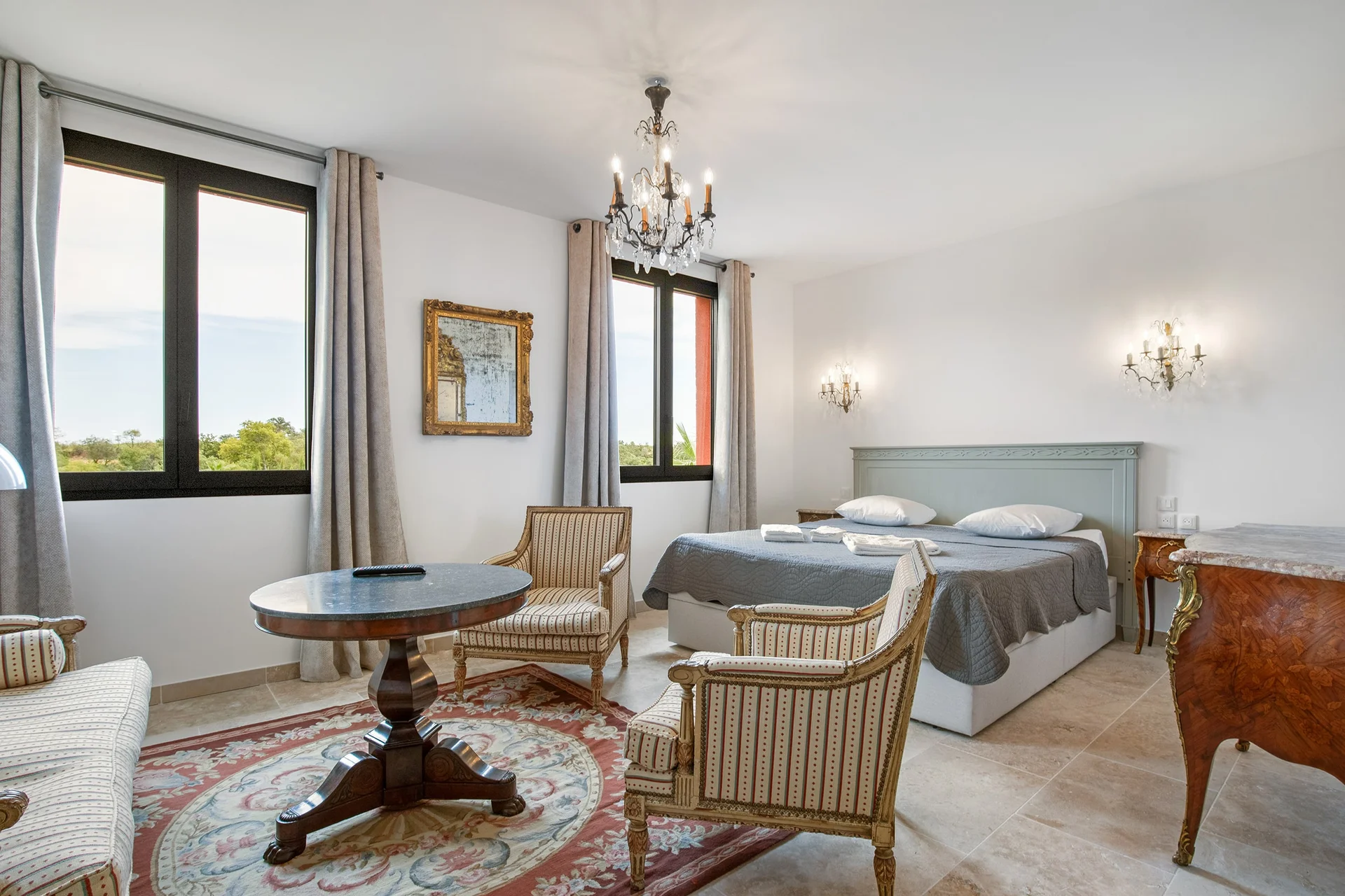 Chambre luxueuse avec lustre en cristal et vue sur le paysage au Château Hermitage de Combas, hébergement mariage Hérault