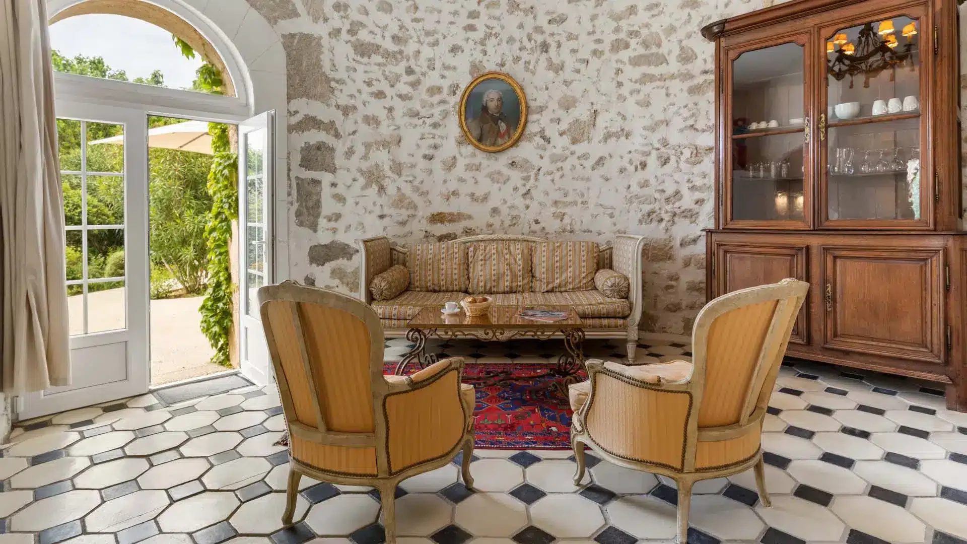 Salon en pierre avec carrelage hexagonal et fauteuils dorés au Château Hermitage de Combas, réception mariage Hérault