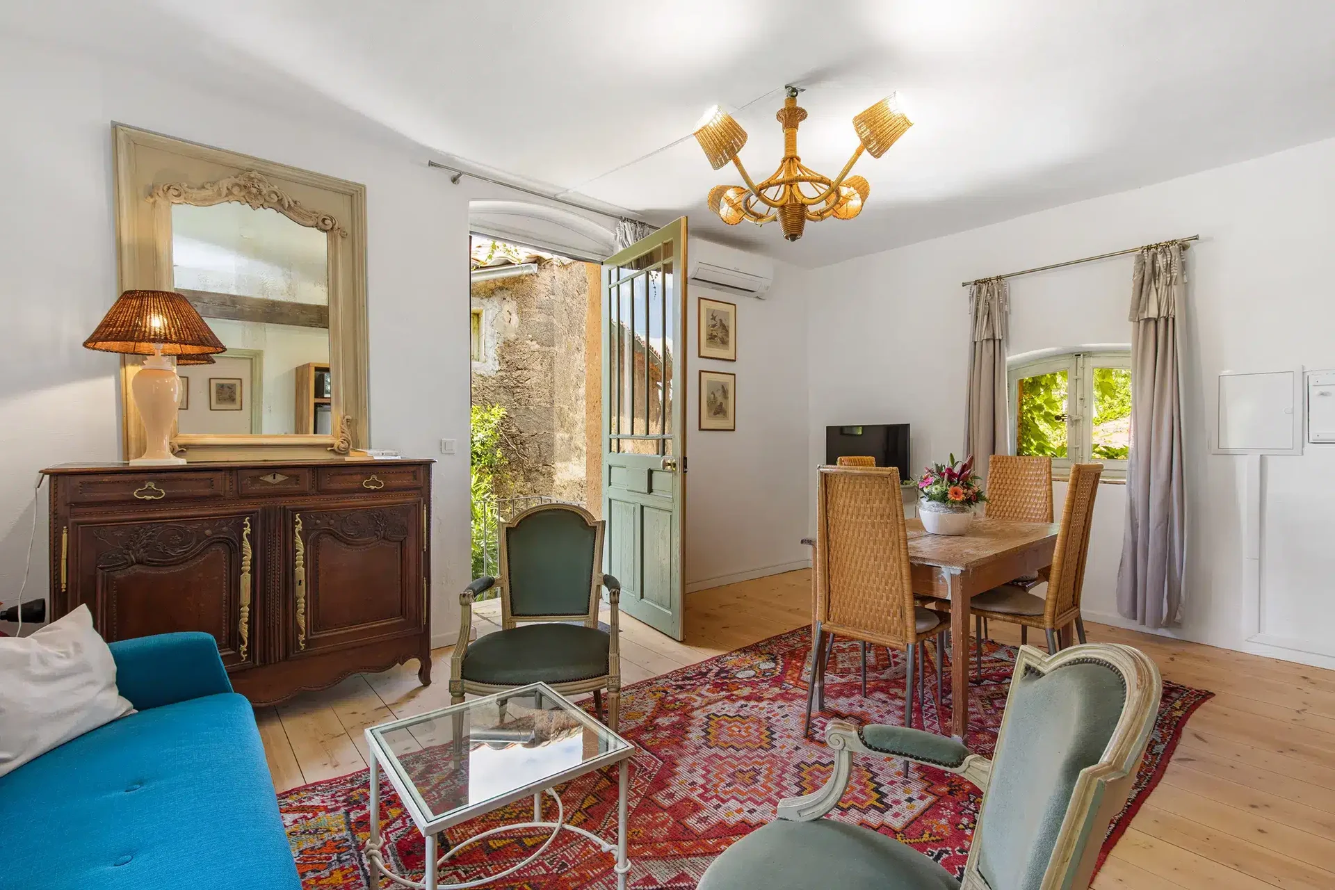 Salon lumineux avec mobilier ancien et porte ouverte sur le château Hermitage de Combas, gîte de mariage Hérault