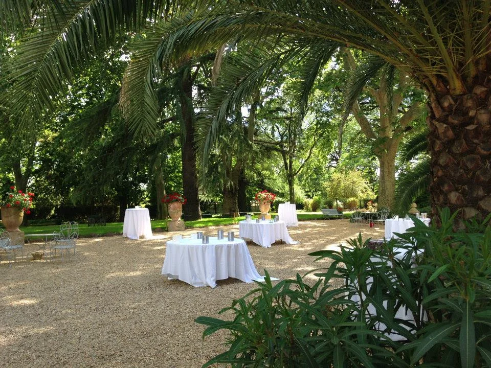 Espace cocktail mariage en plein air sous palmiers au Château La Banquière Hérault avec tables nappes blanches