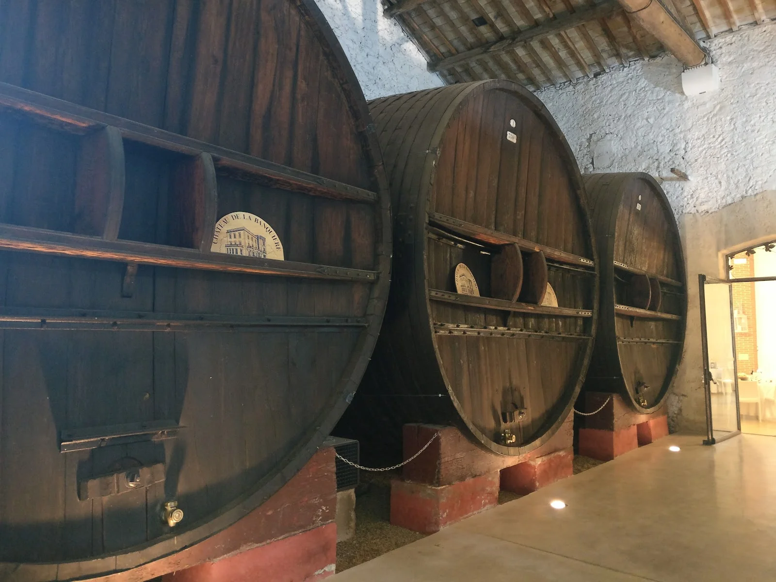 Foudres en chêne centenaires estampillés Château La Banquière Hérault dans cave rénovée pour mariage atypique