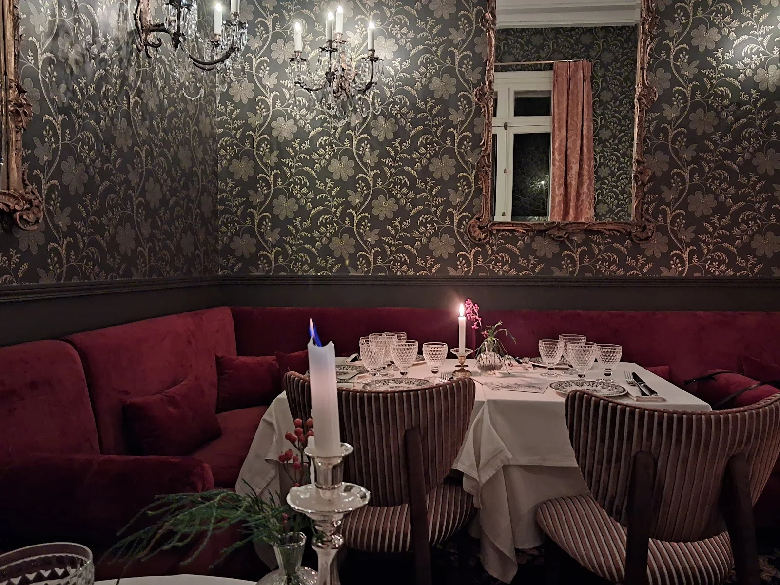 Salon intime du Château Paloma dans l'Hérault avec banquette bordeaux, papier peint doré et bougies pour mariage