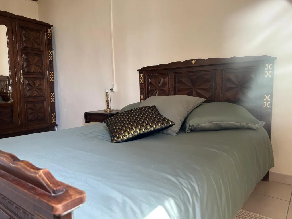 Chambre avec mobilier ancien sculpté et parure vert sauge au Château Périès, hébergement mariage Hérault