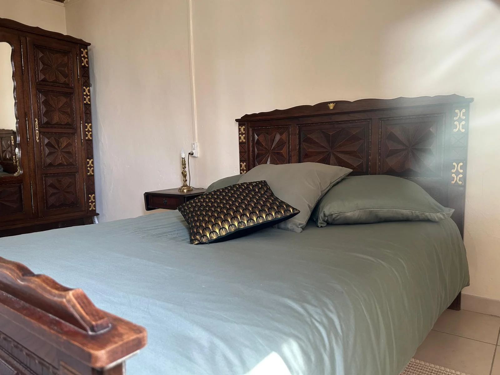 Chambre avec mobilier ancien sculpté et parure vert sauge au Château Périès, hébergement mariage Hérault