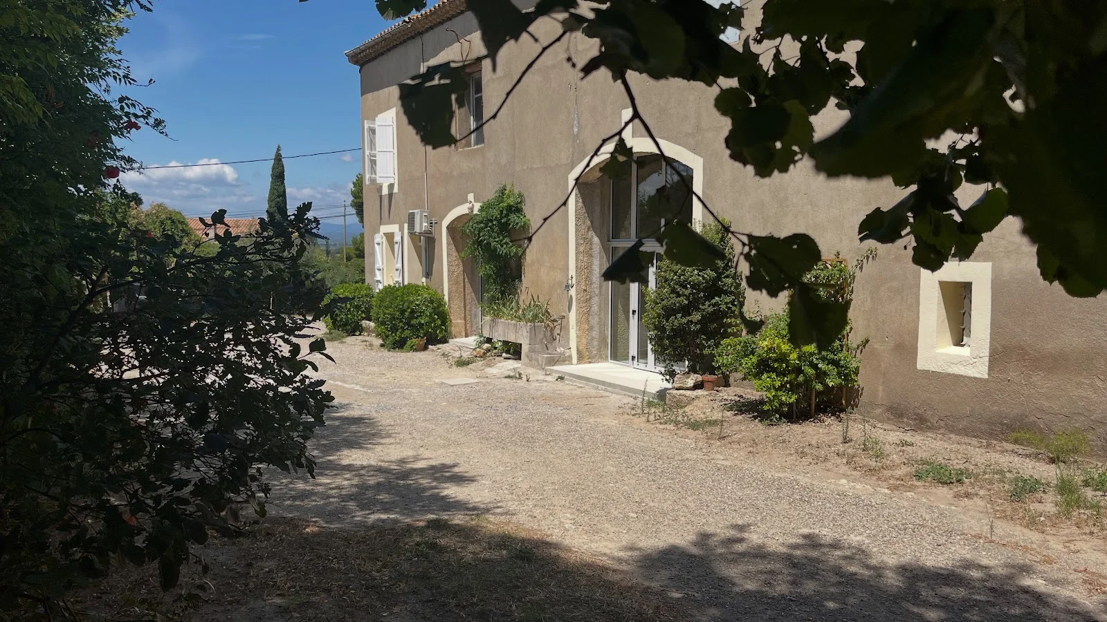 Vue extérieure du Château Périès dans l'Hérault, allée gravillonnée et façade beige pour mariage en Occitanie