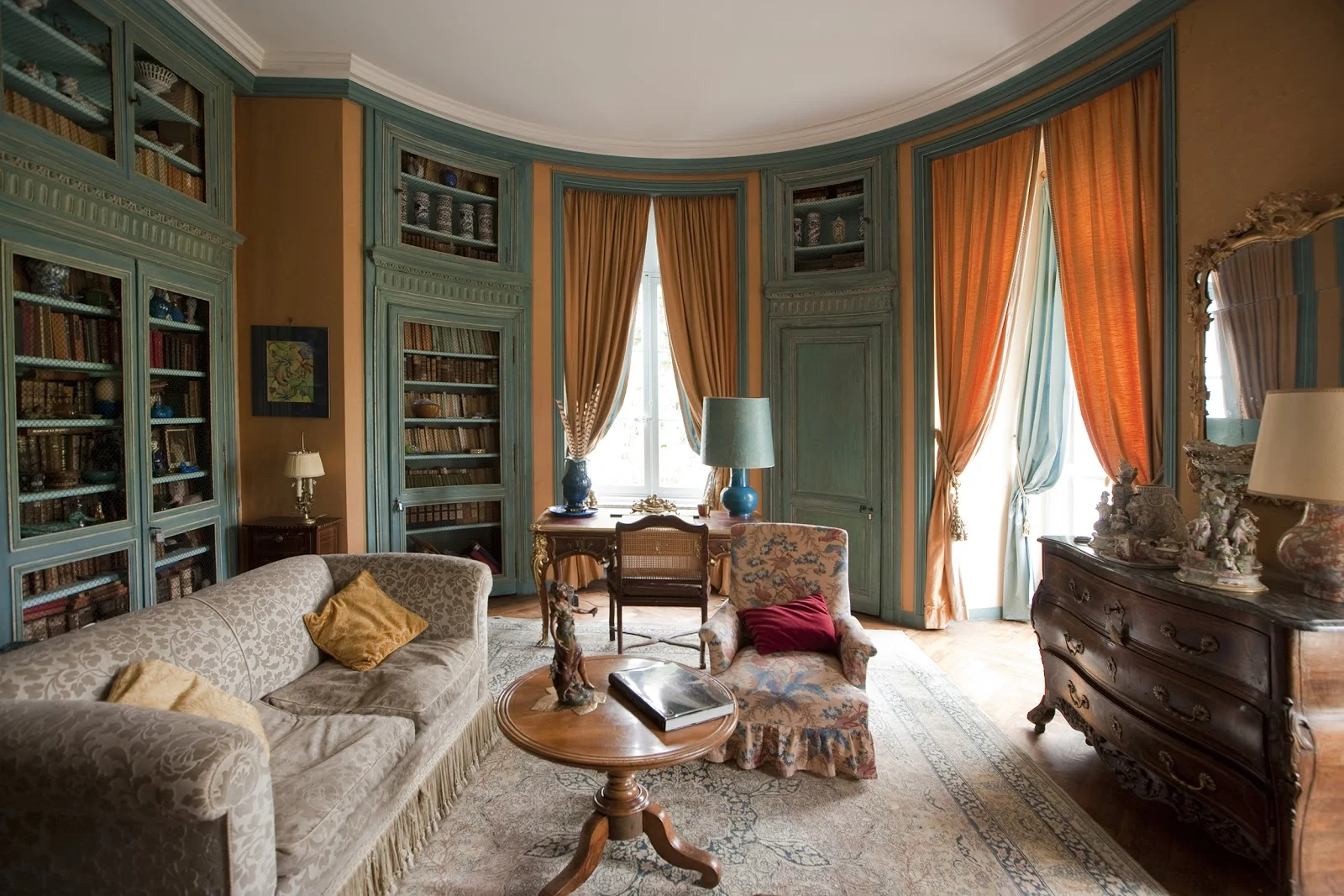 Bibliothèque arrondie Second Empire du Château Raissac Hérault, boiseries bleues et rideaux orange pour réception mariage