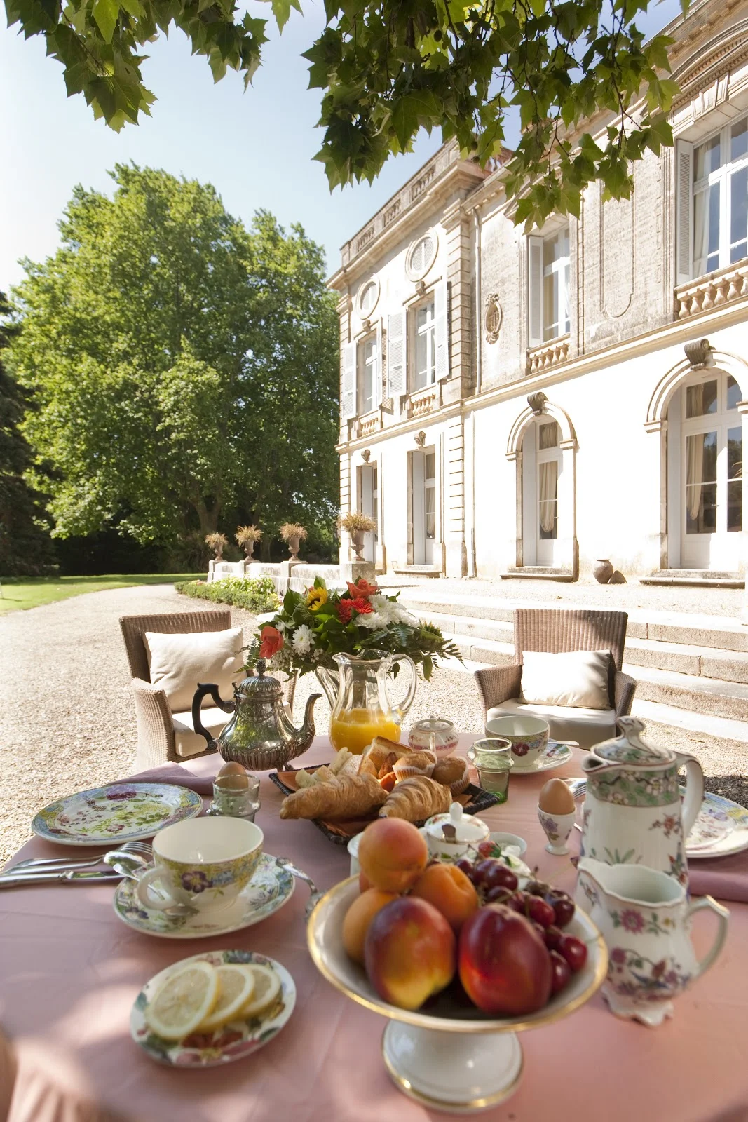 Petit-déjeuner en terrasse face au Château Raissac Hérault, table fleurie avec vaisselle ancienne et viennoiseries pour mariage