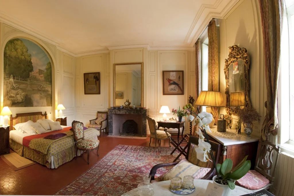 Suite avec fresque murale et cheminée en marbre au Château Raissac Hérault, mobilier Louis XVI et orchidées pour mariage