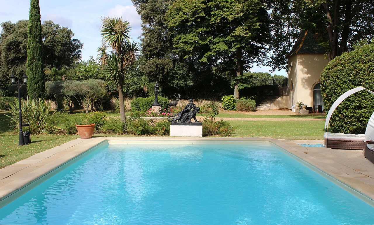 Piscine extérieure, jardin luxuriant, sculptures, bâtisse élégante, ambiance méditerranéenne, Château Rieutort Saint-Pargoire mariage Hérault Occitanie