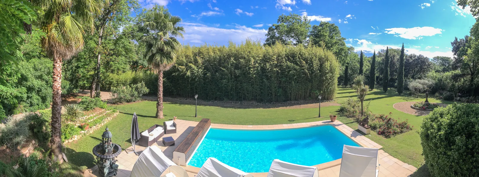 Piscine extérieure, jardin luxuriant, palmiers, cyprès, fontaine, ambiance méditerranéenne, Château Rieutort Saint-Pargoire mariage Hérault Occitanie