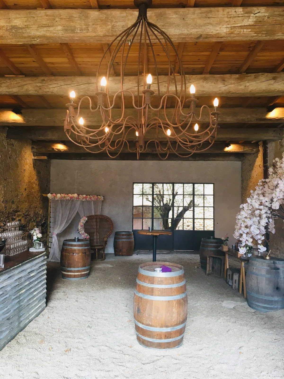 Espace cocktail rustique avec tonneaux et lustre fer forgé au Château Sainte Cécile pour mariage Hérault
