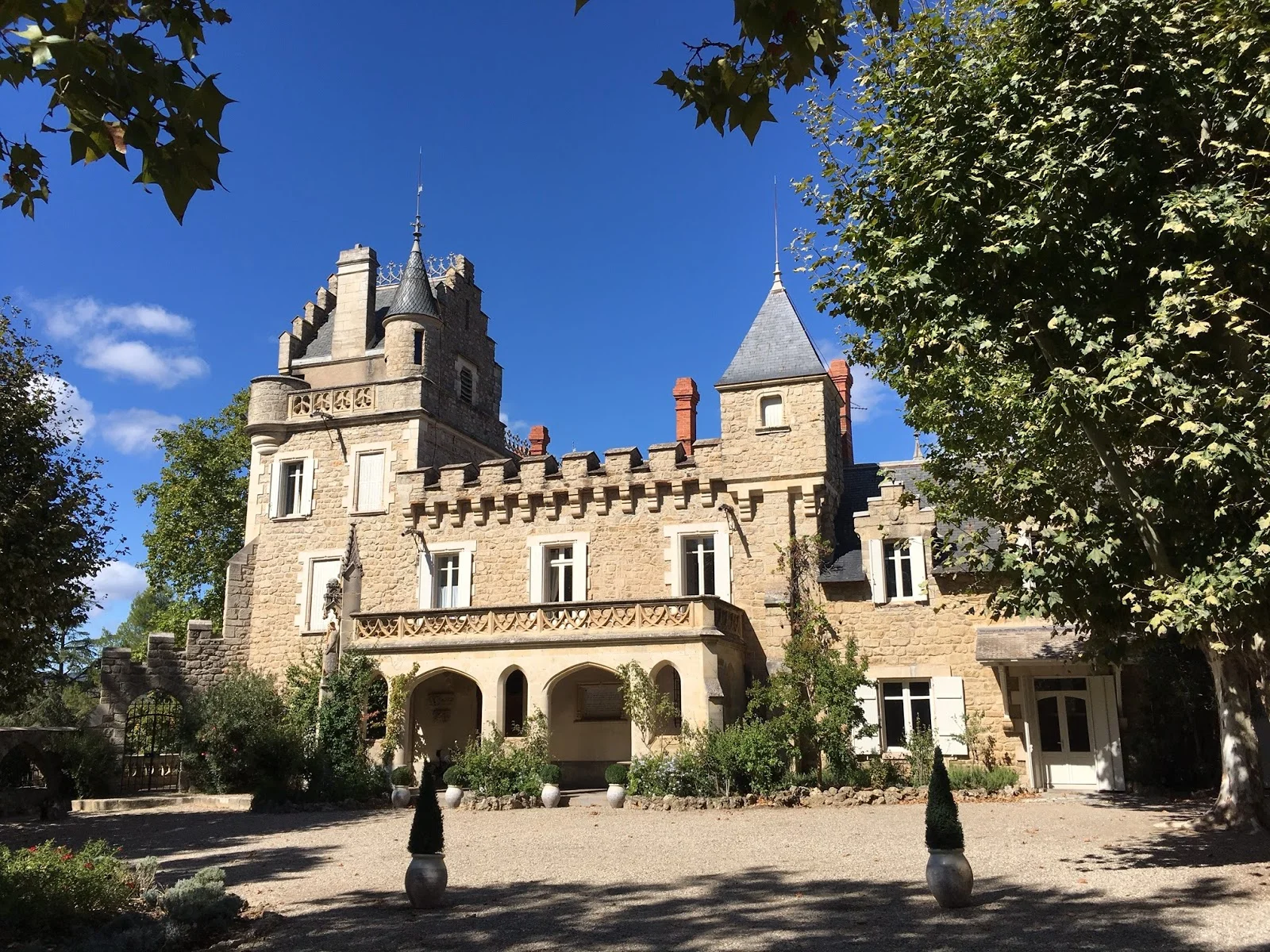 Vue de la cour intérieure du Château St Jean Hérault avec façade en pierre et topiaires pour mariage