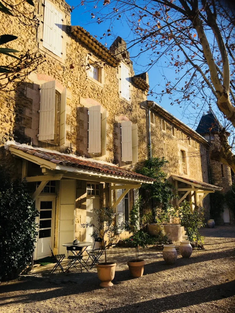 Dépendances en pierre de la cour intérieure du Château St Jean Hérault avec auvent bois et jardinières