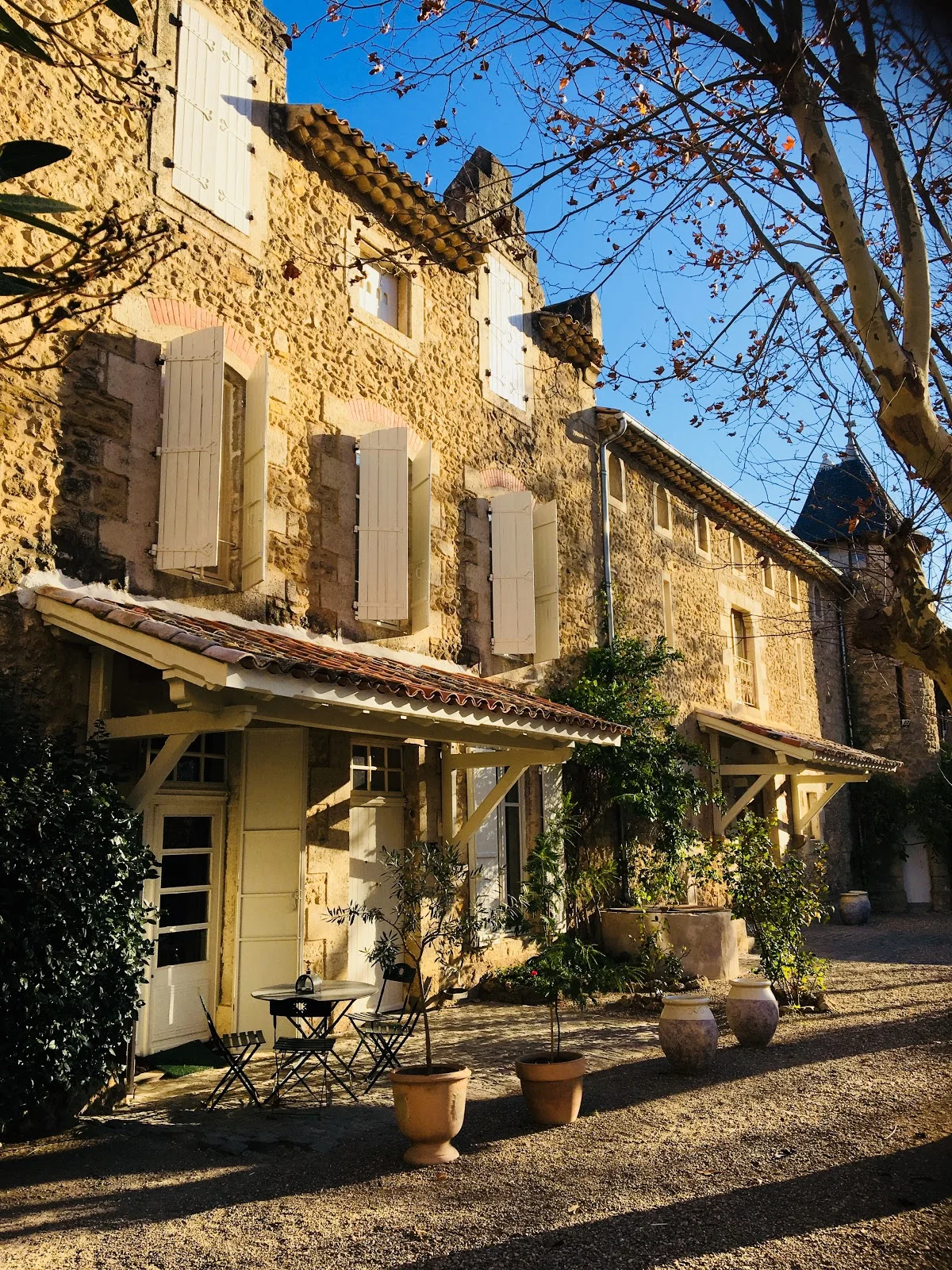 Dépendances en pierre de la cour intérieure du Château St Jean Hérault avec auvent bois et jardinières