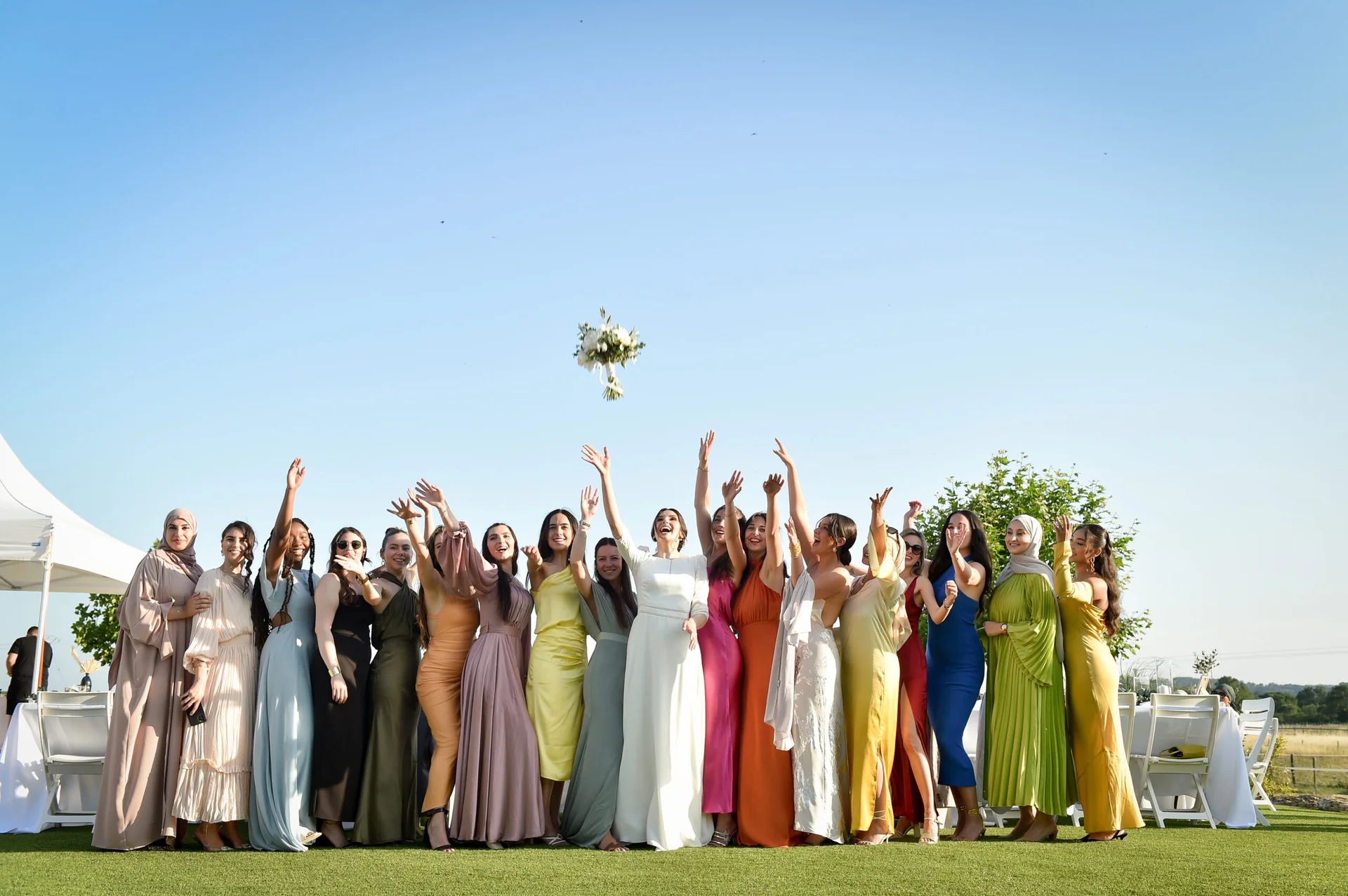 Lancer du bouquet de la mariée entourée d'invitées colorées au Domaine de Christin Hérault