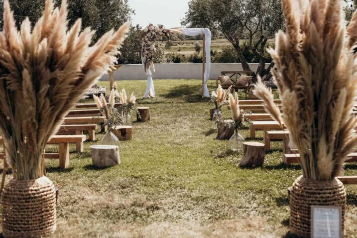 Allée de cérémonie bohème au Domaine de Fangouse Hérault avec herbes de la pampa et arche fleurie sous les oliviers