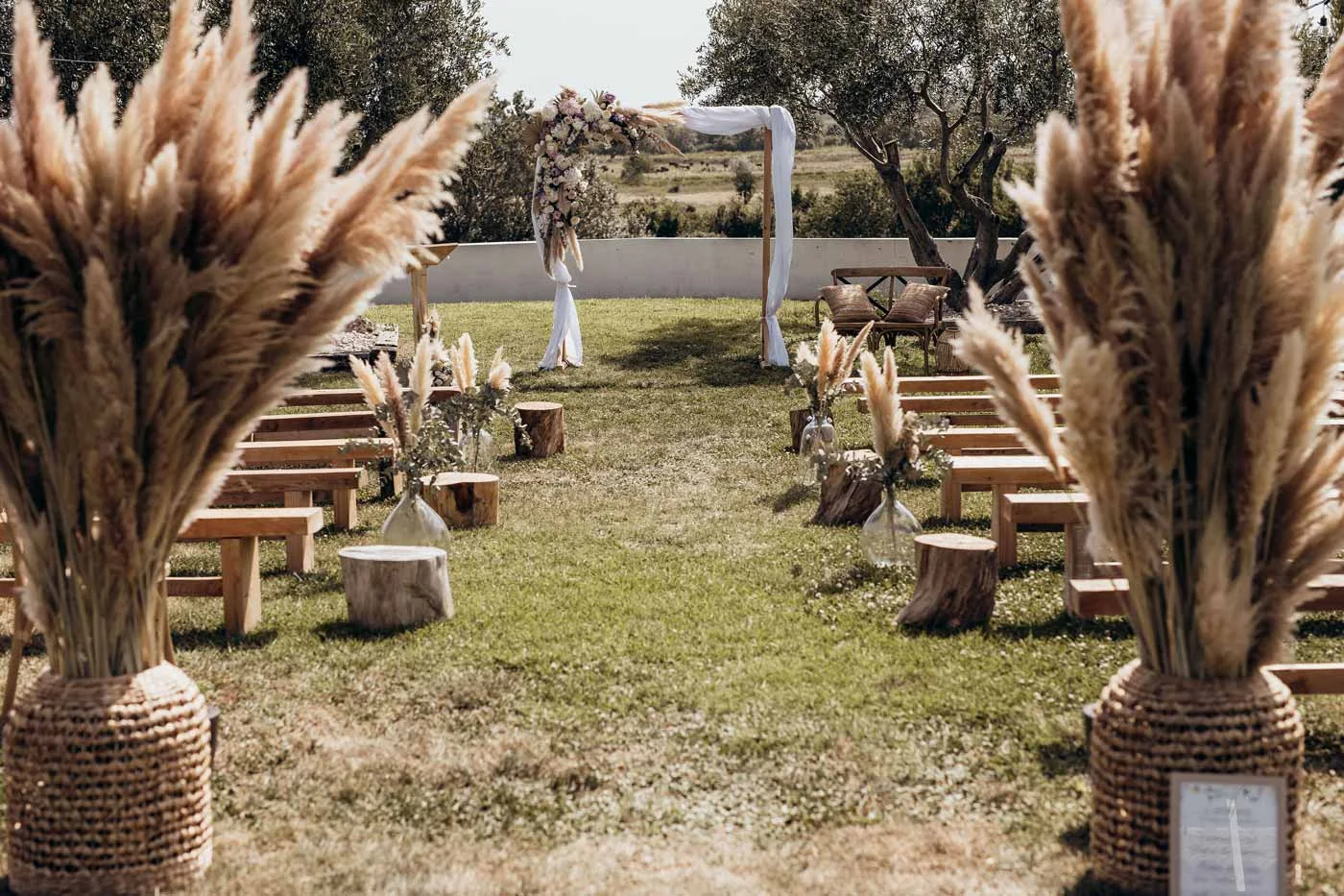 Cérémonie laïque extérieure au Domaine de Fangouse Hérault, allée avec arche fleurie et herbes de la pampa