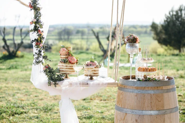Table de desserts mariage avec naked cake fleuri et tonneau bois en extérieur au Domaine de Fangouse Hérault