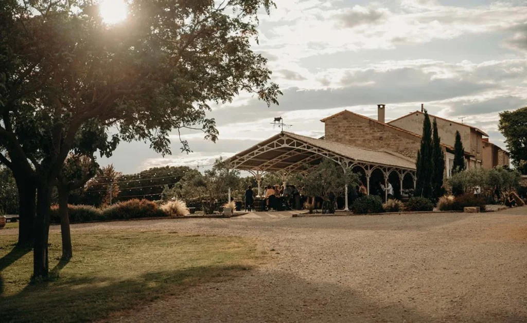 Vue extérieure du Domaine de Fangouse dans l'Hérault au coucher du soleil, préau blanc et bâtisse en pierre pour mariage