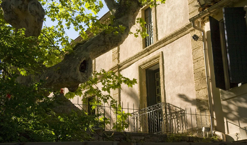 Façade mas provençal en pierre avec balcon fer forgé et platane centenaire au Domaine de la Clapière Hérault