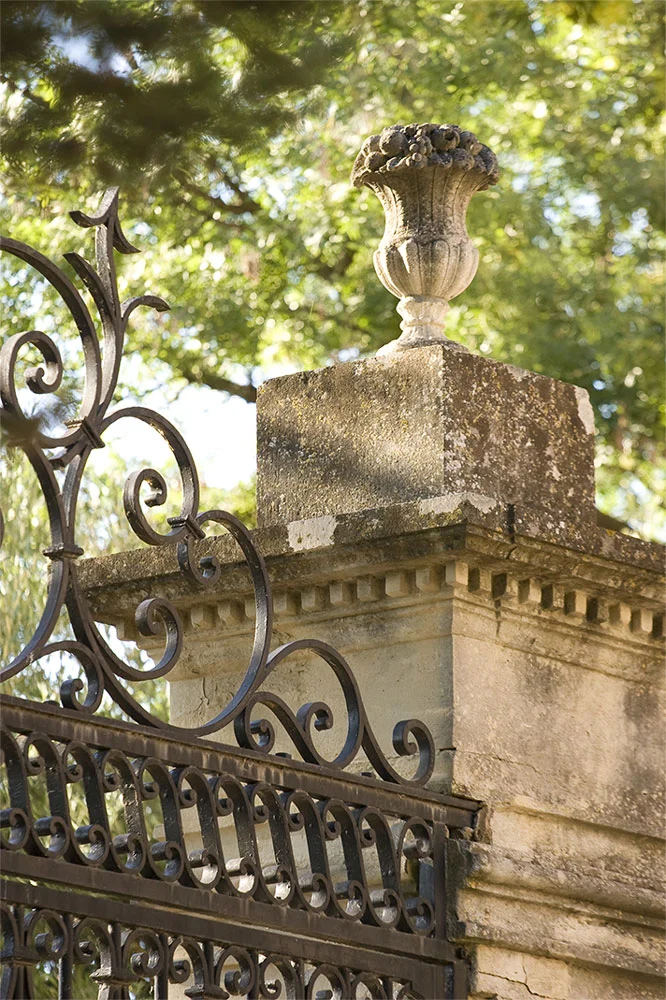Pilier en pierre calcaire avec urne sculptée et portail en fer forgé au Domaine de la Clapière, mariage Hérault